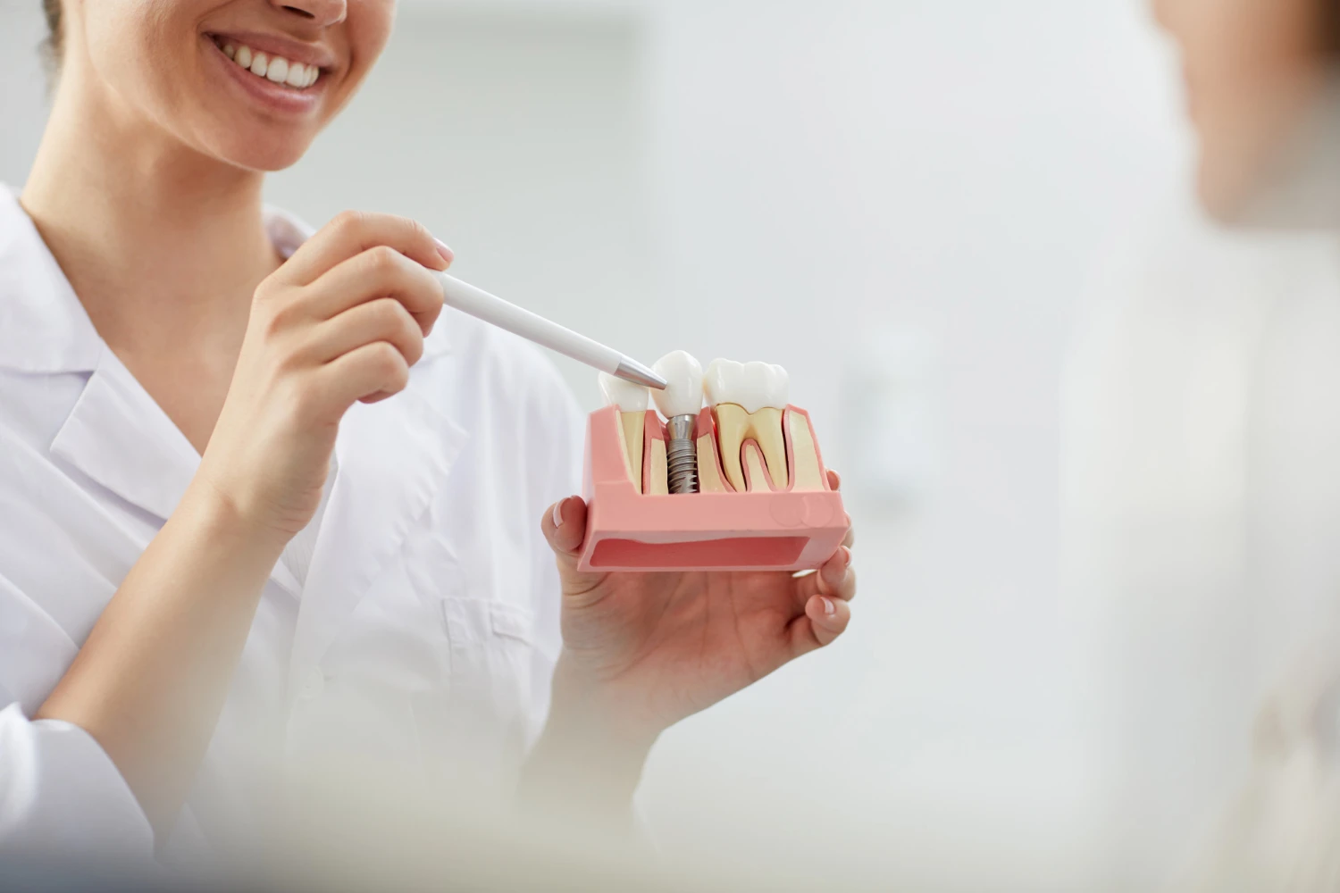 Hekim elindeki implant eğitim modelini işaret çubuğuyla gösteriyor